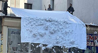 Vatandaşlar çatıdaki kar kütlelerini brandayla indirdi