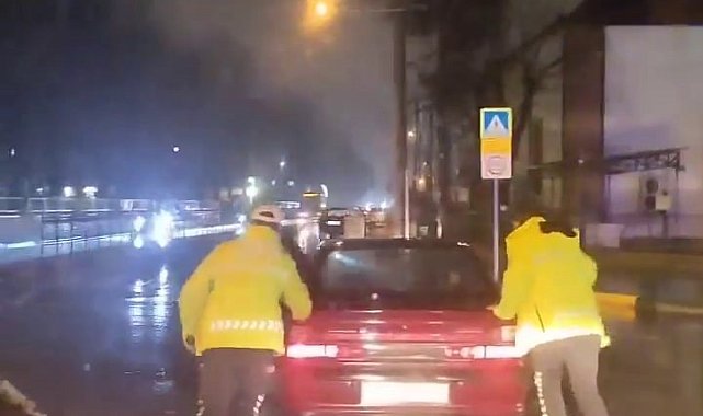 Arızalanan otomobili trafik polisleri yağmurun altında itti