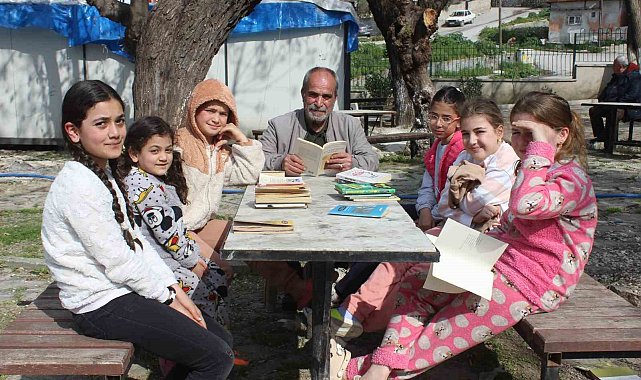 Eline kitabı alan muhtar, çocuklara örnek olmak için birlikte kitap okuyor