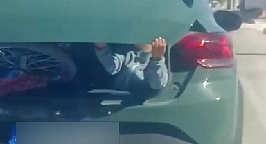 Minik elleriyle hem kendini hem de bagaj kapağını tuttu