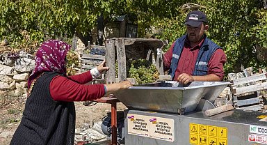 Üzüm sıkma makinesi çalışıyor, üretici keyfine bakıyor